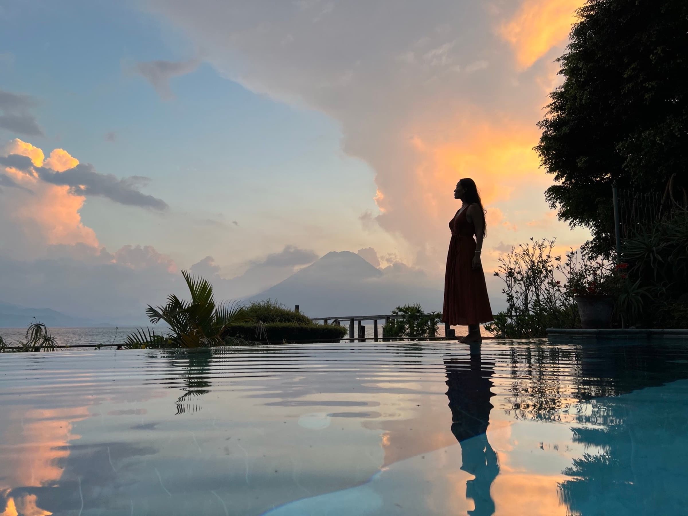 A guest at the infinity pool's edge at sunset, Lake Atitlán beyond